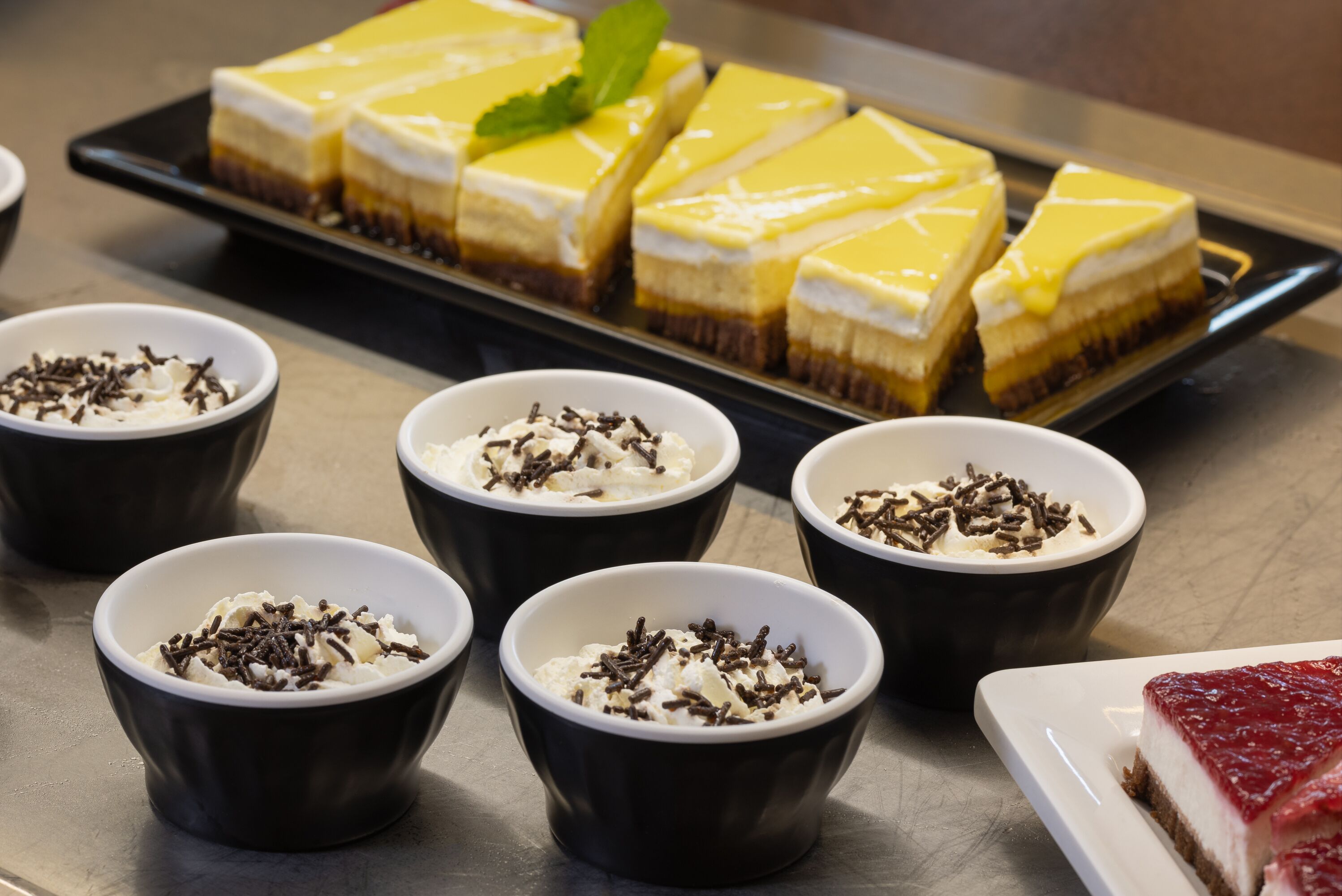 Un présentoir de desserts avec divers gâteaux et des coupes de crème fouettée garnies de copeaux de chocolat.