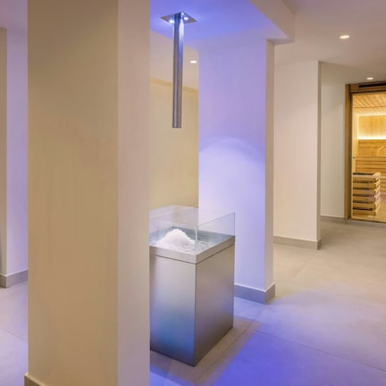 A hallway with a modern design, featuring a glass display case and a wooden door with a built-in bench.