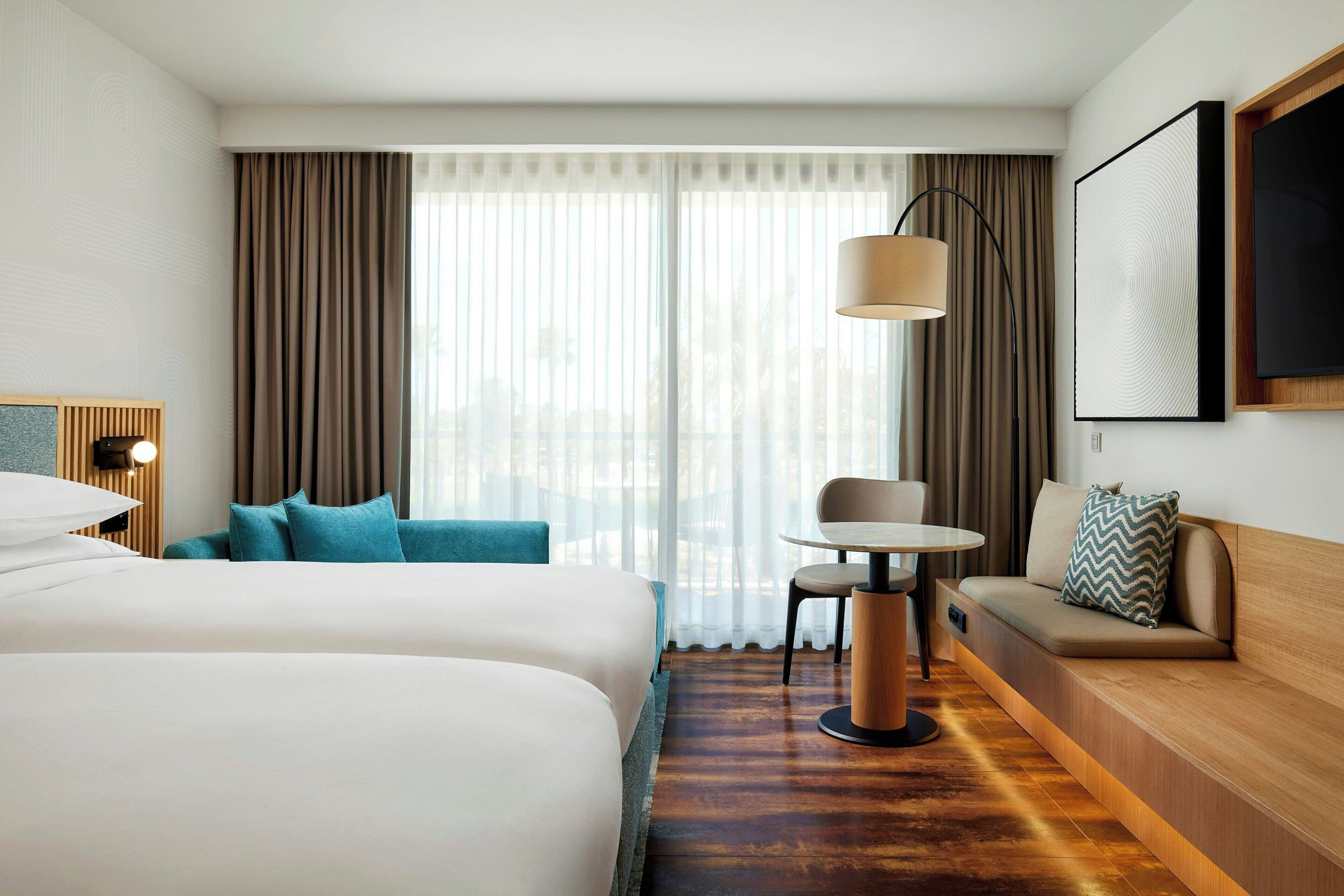 A hotel room with two beds, a sofa, a small table, and a lamp.