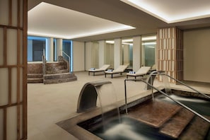 A spa area with a hot tub, lounge chairs, and a staircase leading to a higher level.