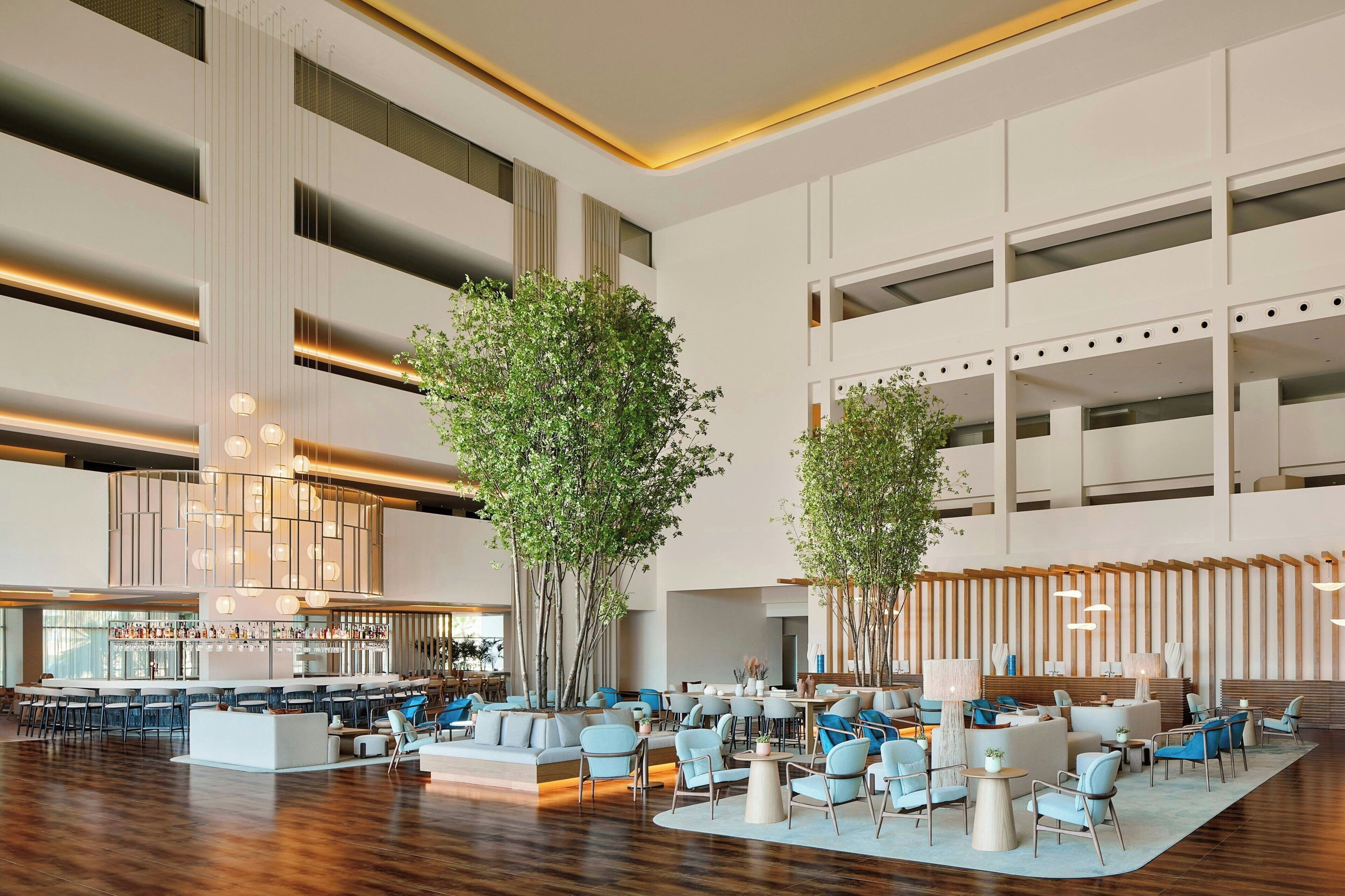 A spacious lobby with a central seating area, a bar, and a staircase.