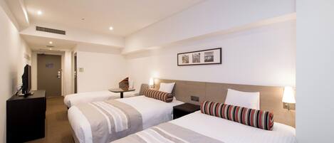 A hotel room with two beds, a desk, a TV, and a framed picture on the wall.