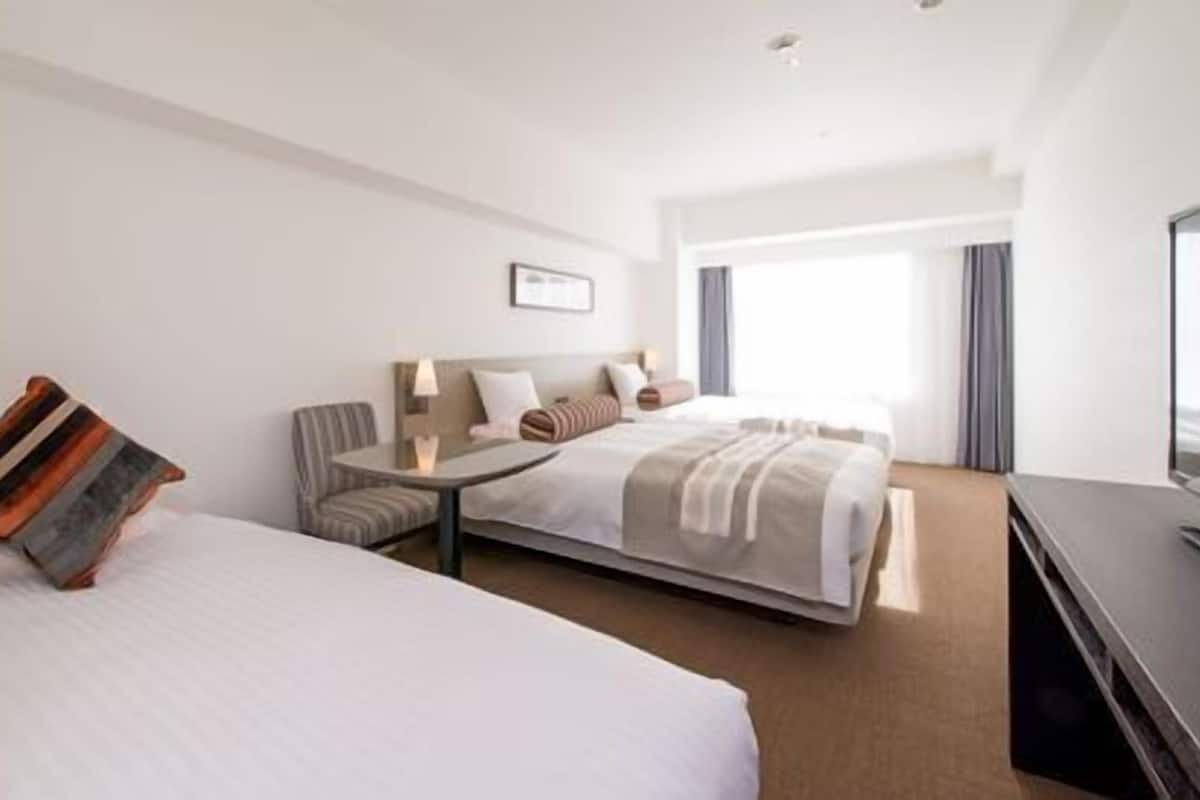 Ein Hotelzimmer mit zwei Betten, einem kleinen Tisch, einem Stuhl und einem Fernseher.