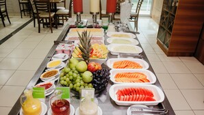 Un bufé con diversas frutas, verduras y salsas.
