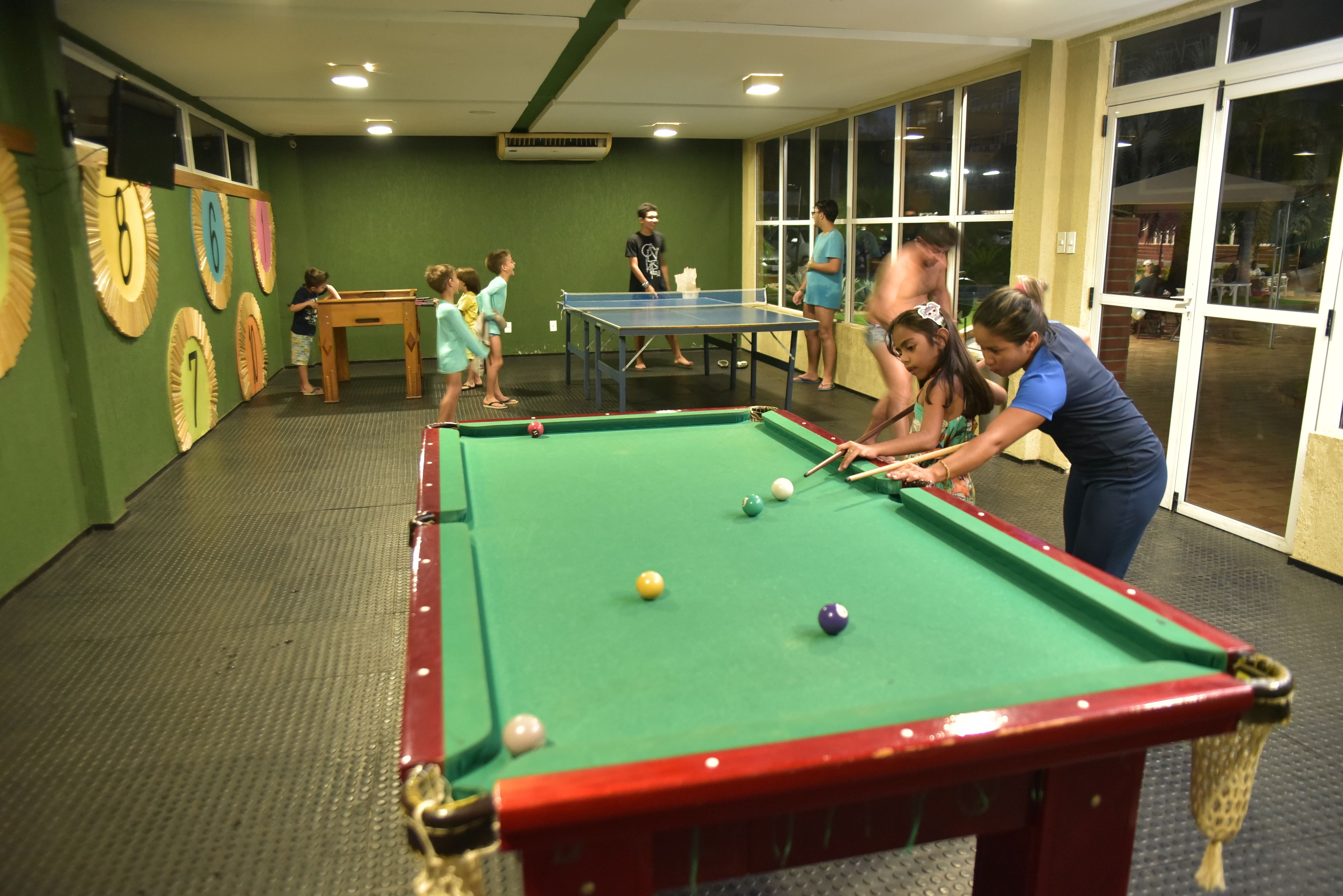 A pool table in a room with green walls and a window.