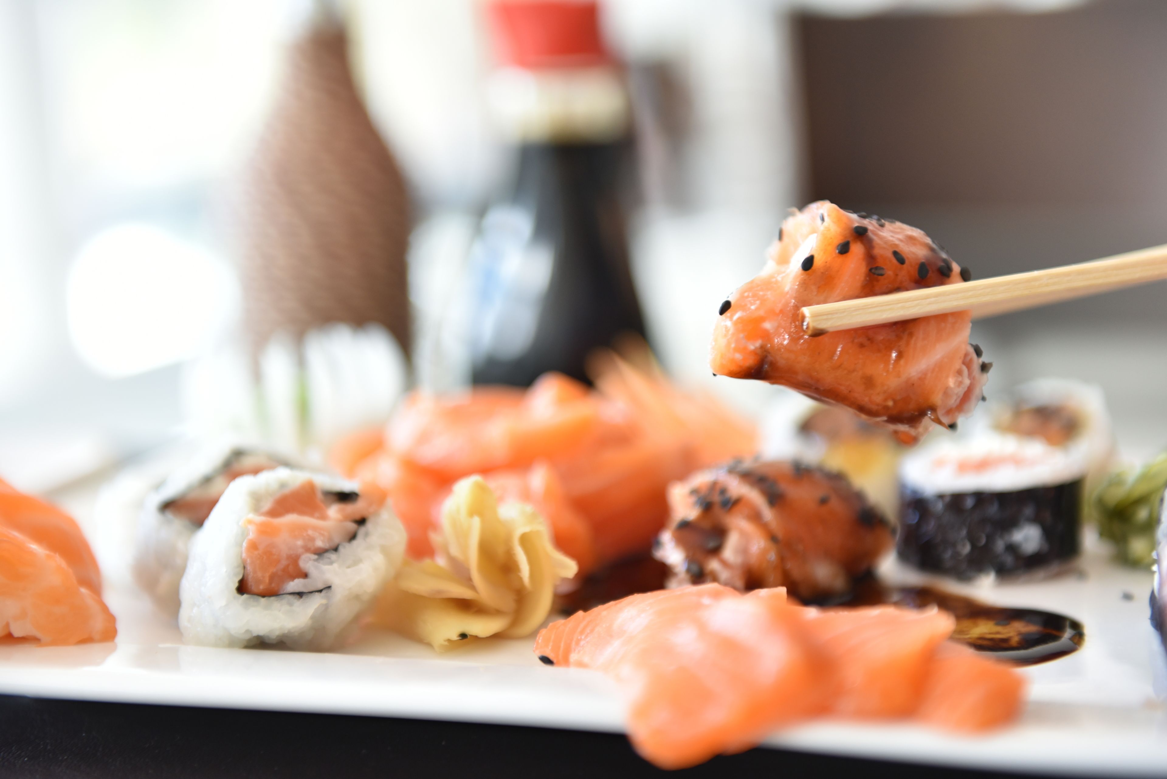 Un plato de sushi con diferentes variedades, incluyendo nigiri y rollos, acompañado de salsa de soja y wasabi.