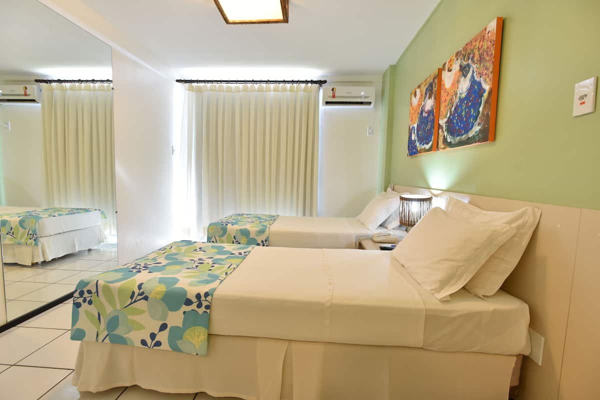 A hotel room with two beds, a large mirror, and a painting on the wall.