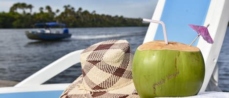 En strandstol med en hatt och en drink med kokosmjölk, sugrör och parasoll.