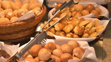 Un bufé con diversas opciones de panadería, incluyendo pan, pasteles y bollos.