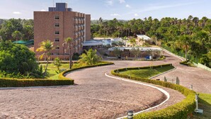 A hotel with a brick building, a curved driveway, and a pool area surrounded by greenery. - Hotel Gran Lençóis Flat (Barreirinhas)