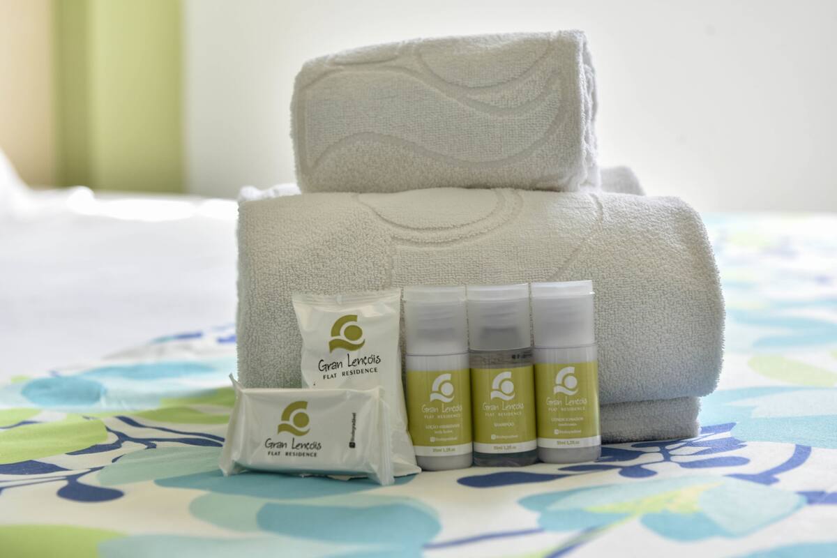 A neatly arranged set of towels and toiletries on a bed with a floral bedspread.