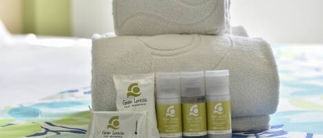 A neatly arranged set of towels and toiletries on a bed with a floral bedspread.