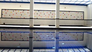 Piscina com paredes azulejadas e uma estrutura no teto.