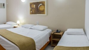 Quarto de hotel com duas camas de solteiro, mesa de cabeceira com telefone e uma obra de arte pendurada na parede.