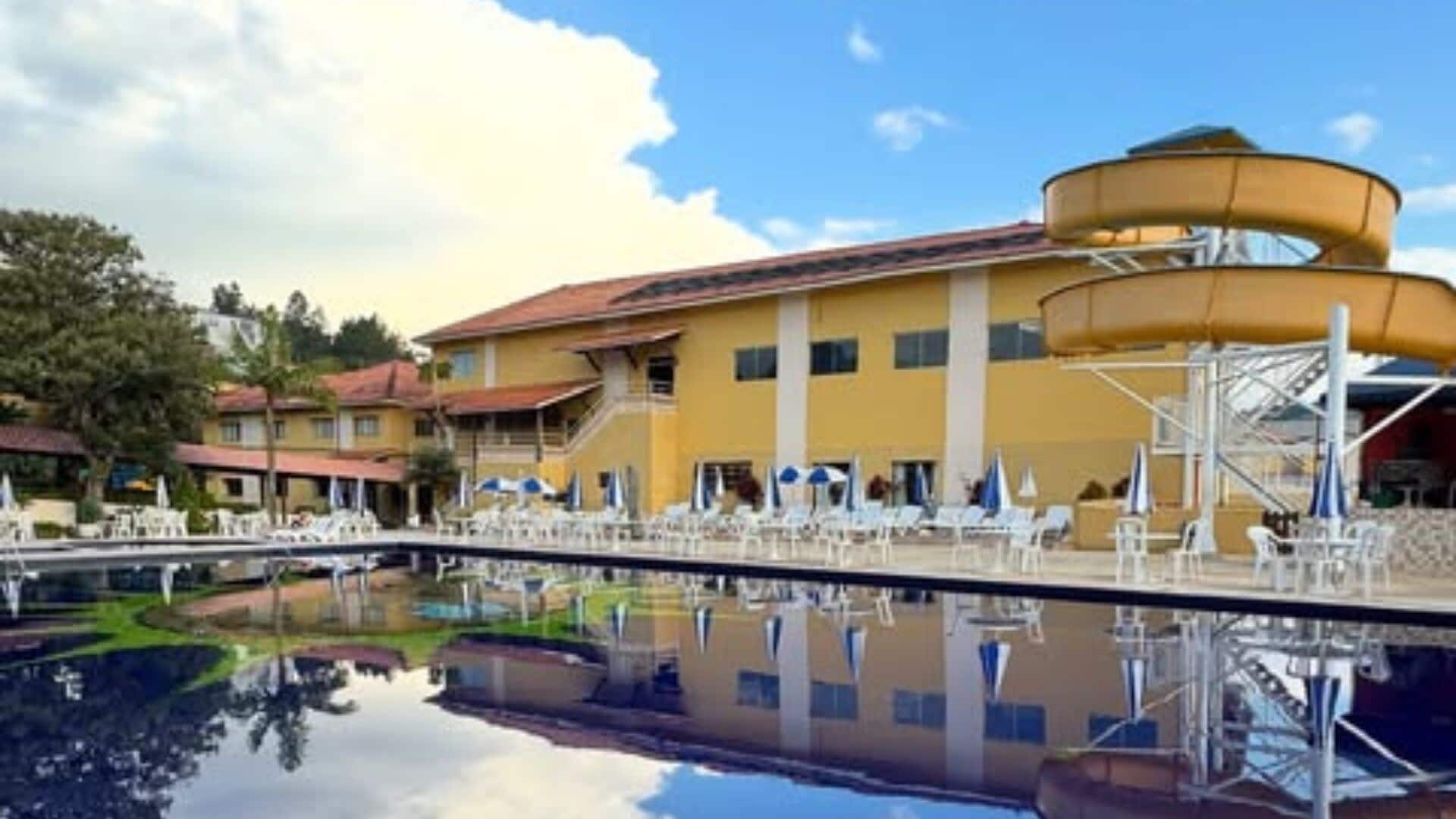 A hotel with a swimming pool, a water slide, and multiple lounge chairs.