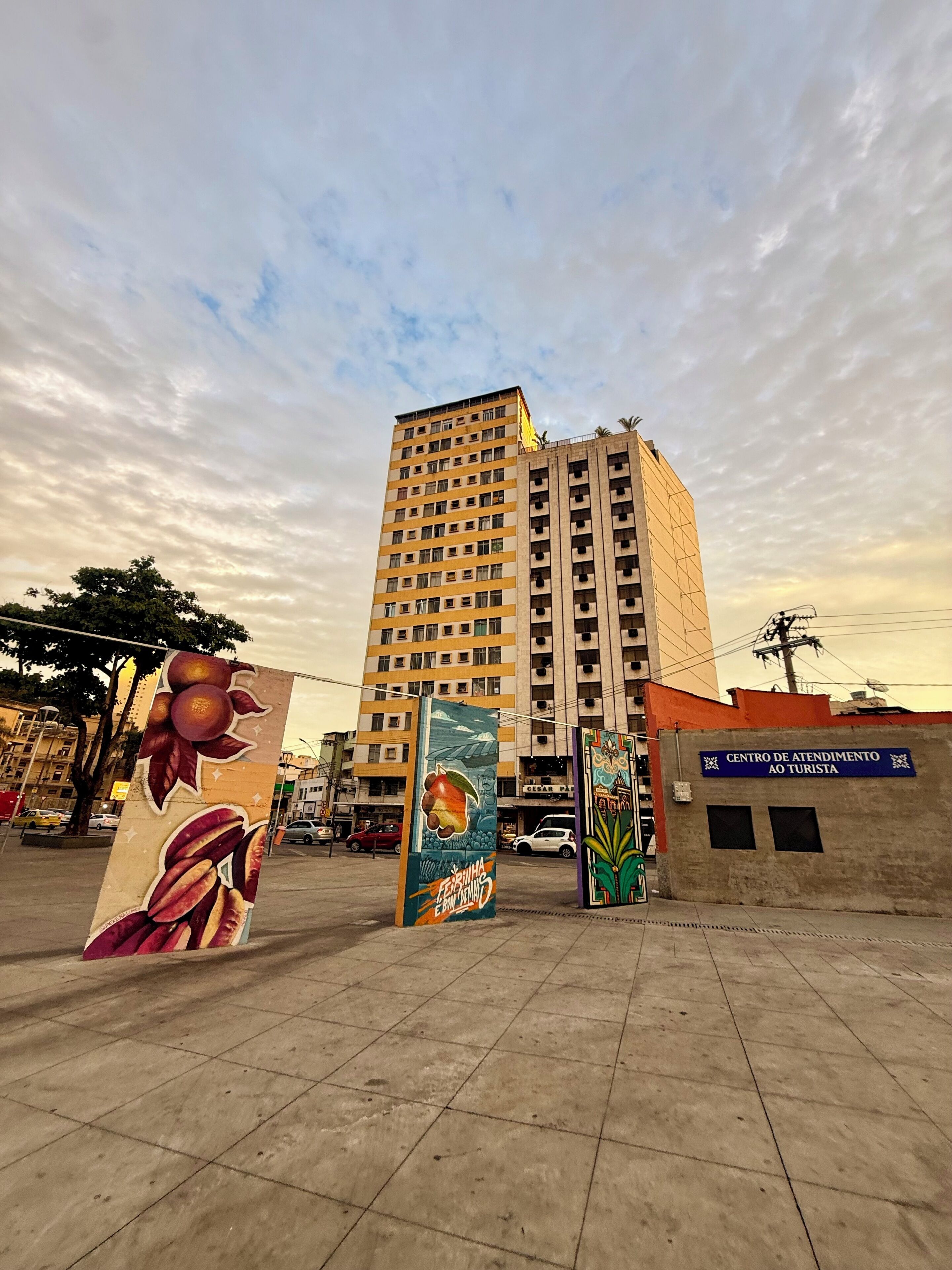 A tall building with multiple floors, a sign for a tourist center, and a mural with fruit and nature.