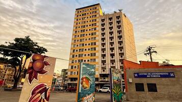 A tall building with multiple floors, a sign for a tourist center, and a mural with fruit and nature.