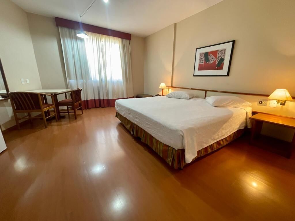 A hotel room with a bed, a desk, and a chair.