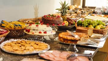 A buffet with various food items including cakes, fruits, and pastries.