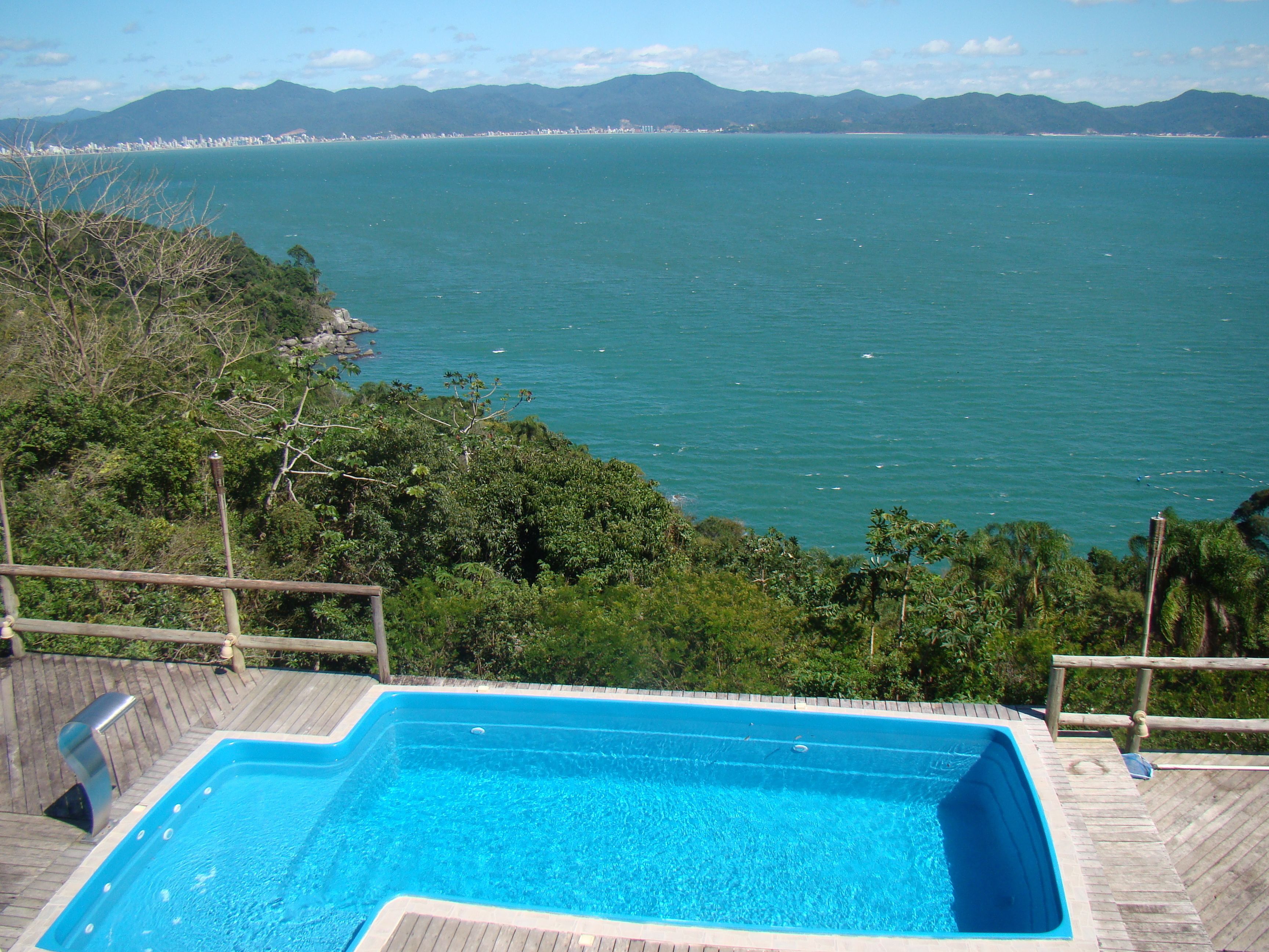Una piscina con cubierta de madera y vista al mar y a las montañas.
