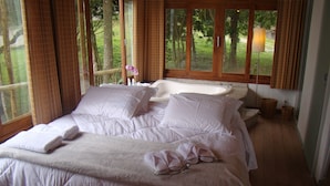 A bedroom with a large bed, a window, and a view of trees. - Pousada The Goldeneye (Porto Belo)