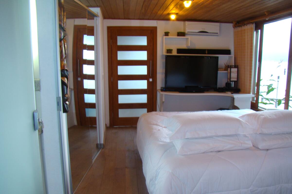 A bedroom with a bed, a television, and a door leading to another room.