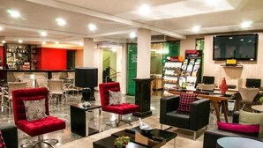 A hotel lobby with a bar area, seating arrangements, and a television screen. - Alves Hotel (Marilia)