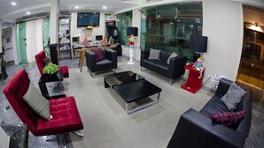 A modern hotel lobby with a curved ceiling, a reception desk, and seating areas with red and black sofas. - Alves Hotel (Marilia)