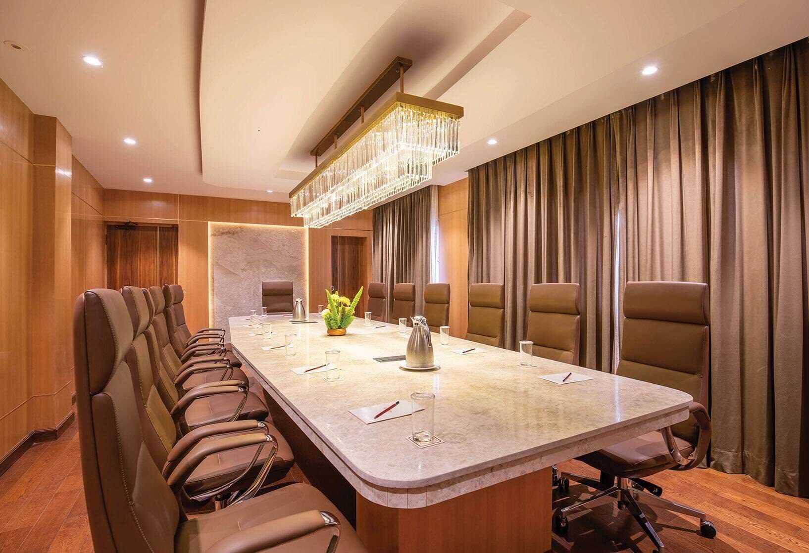 A conference room with a long table, leather chairs, a chandelier, and a curtain backdrop.