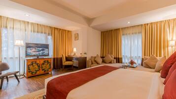 Una habitación de hotel con una cama grande, un escritorio con una silla, un televisor y un sofá.