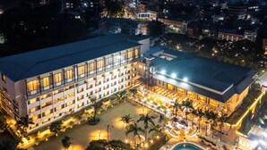 A hotel with multiple floors, a swimming pool, and a well-lit courtyard with palm trees. - Hotel Himalaya Kathmandu - Your Business & Leisure Retreat (Lalitpur)