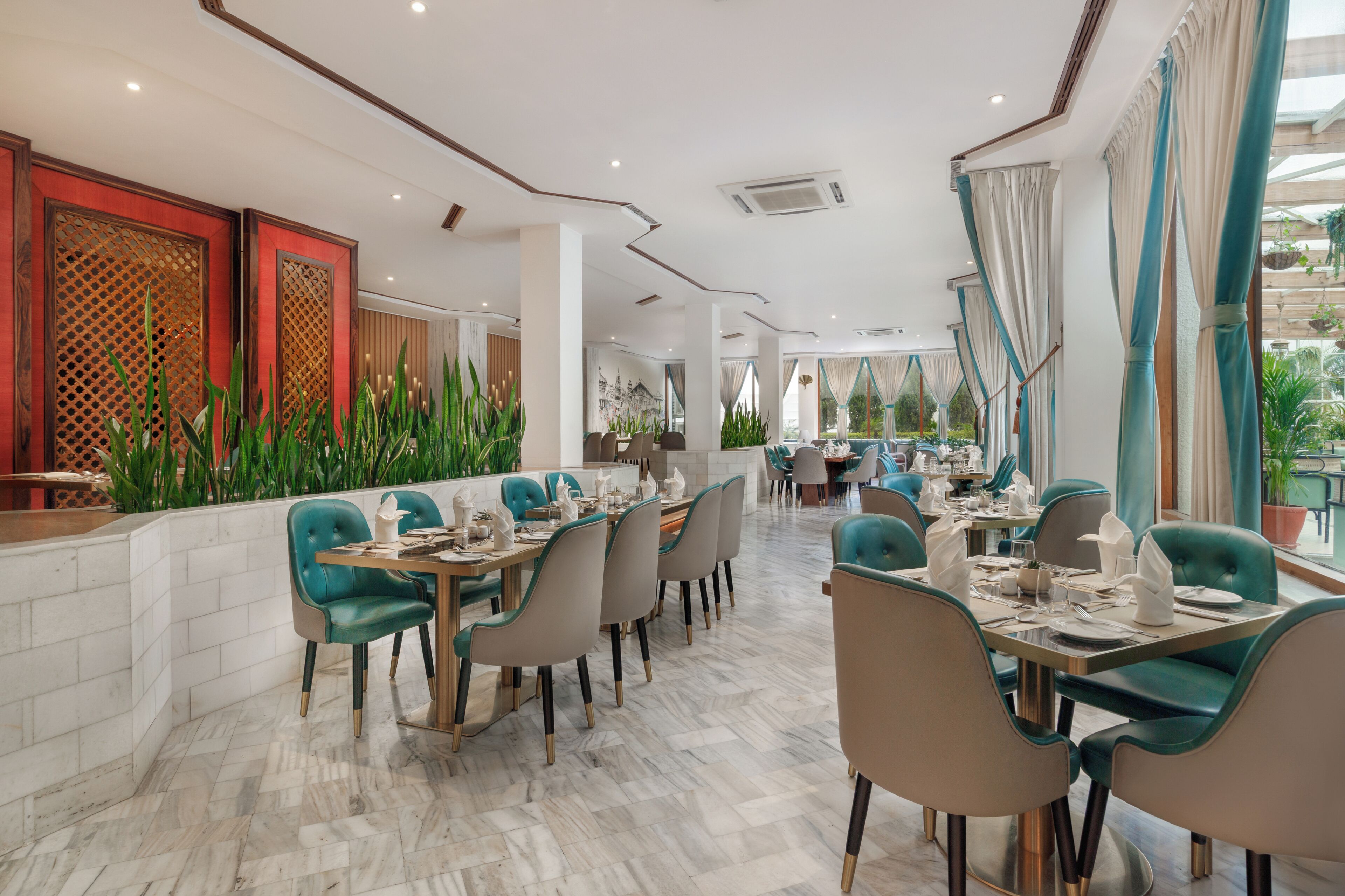 A modern restaurant with a long dining area, multiple tables, and chairs.