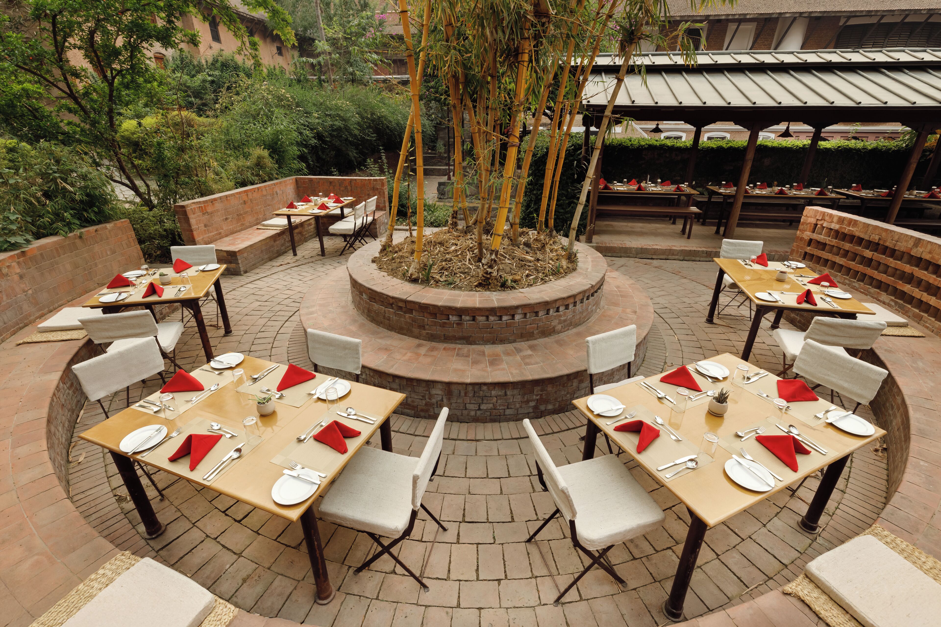 An outdoor dining area with round tables, white chairs, and red napkins.