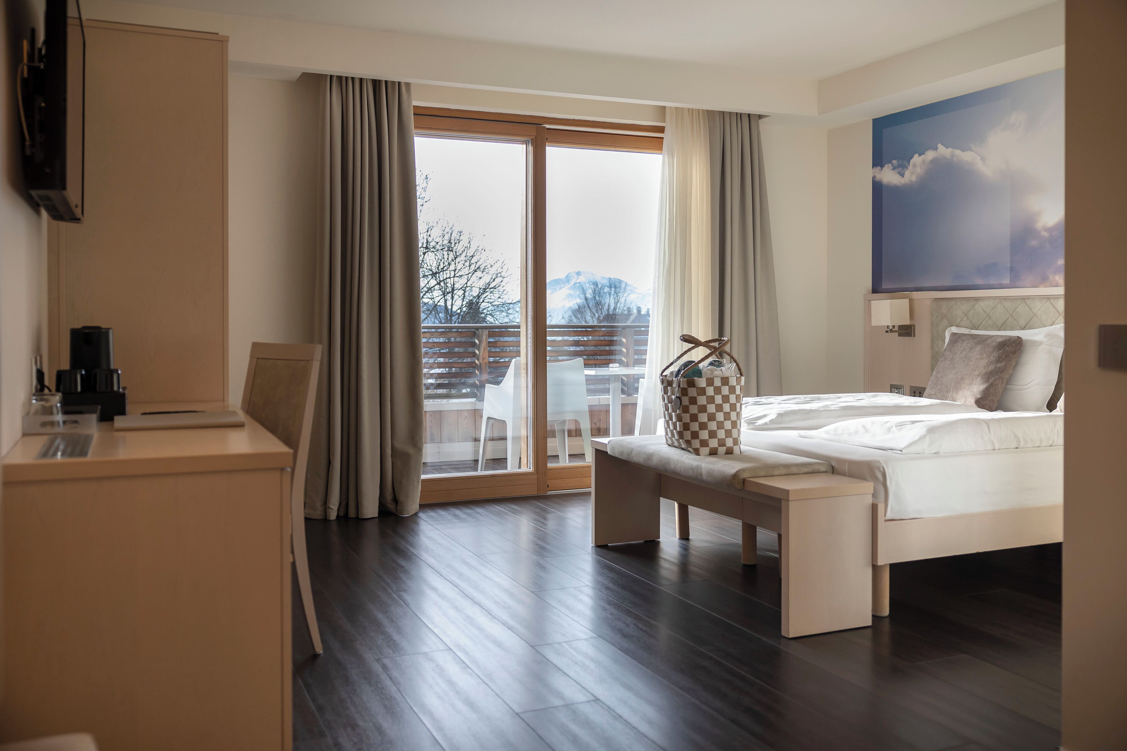 Ein modernes Hotelzimmer mit einem großen Bett, einem Schreibtisch und Blick ins Freie.