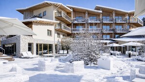 A multi-story hotel with outdoor seating and a pool area, surrounded by snow. - Blu Hotel Natura & Spa - Adults Only (Folgaria)