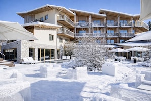 A multi-story hotel with outdoor seating and a pool area, surrounded by snow. - Blu Hotel Natura & Spa - Adults Only (Folgaria)