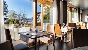A modern dining area with large windows, wooden furniture, and a view of the surrounding landscape. - Blu Hotel Natura & Spa - Adults Only (Folgaria)