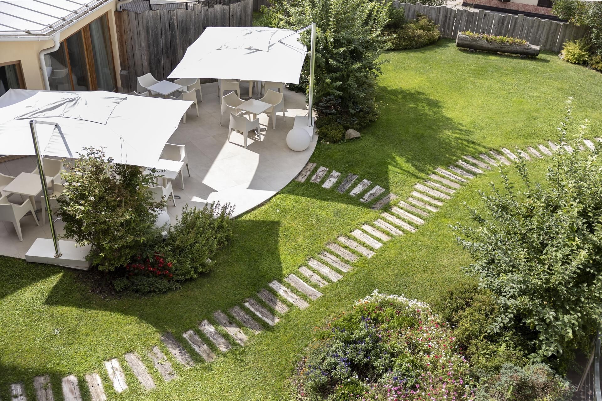 A backyard with a patio area, outdoor furniture, and a garden with a wooden path.