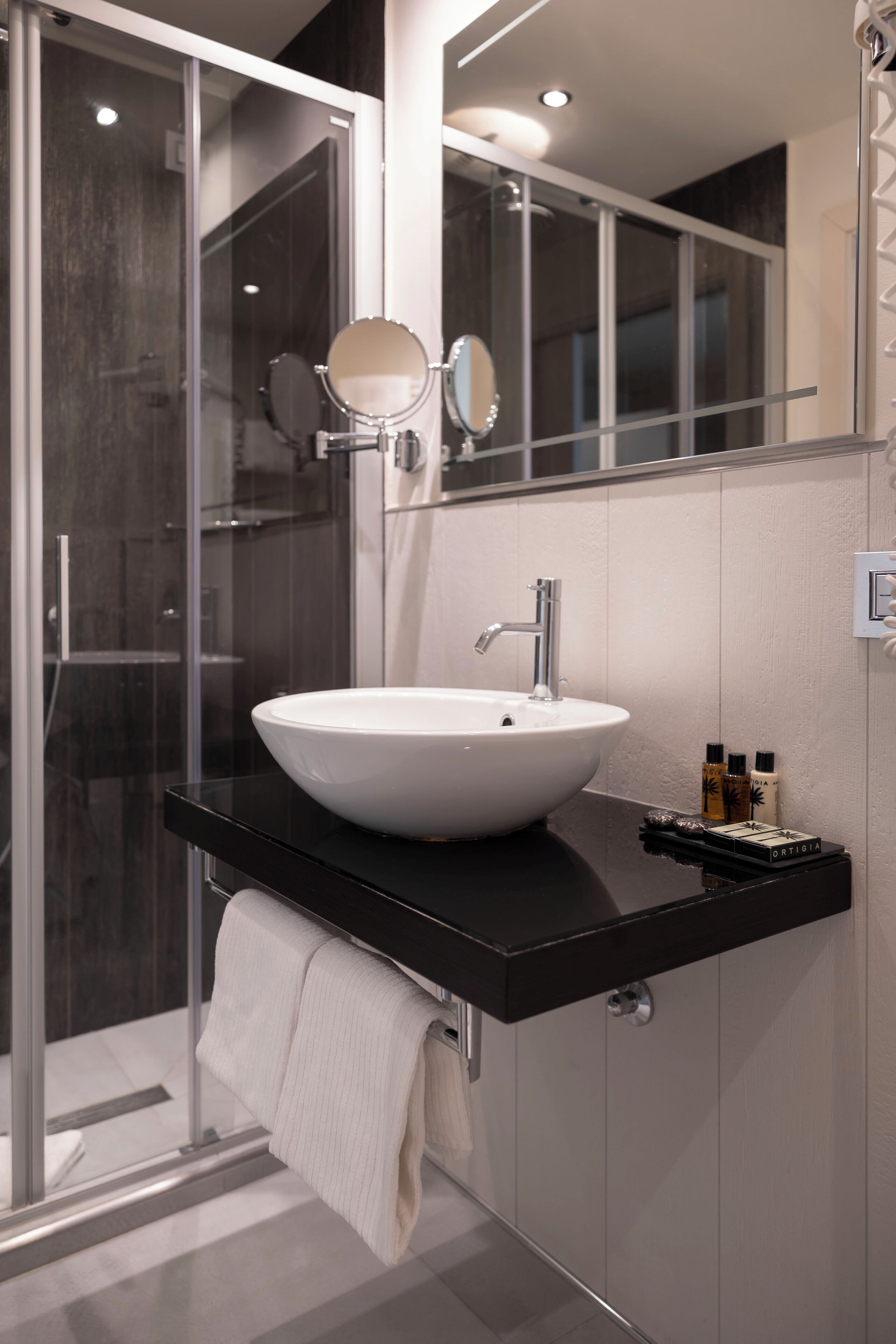 A modern bathroom with a large white sink, a mirror, and a glass shower enclosure.