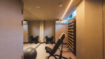 Un gimnasio con equipo de ejercicio, un espejo en la pared y iluminación empotrada en el techo.