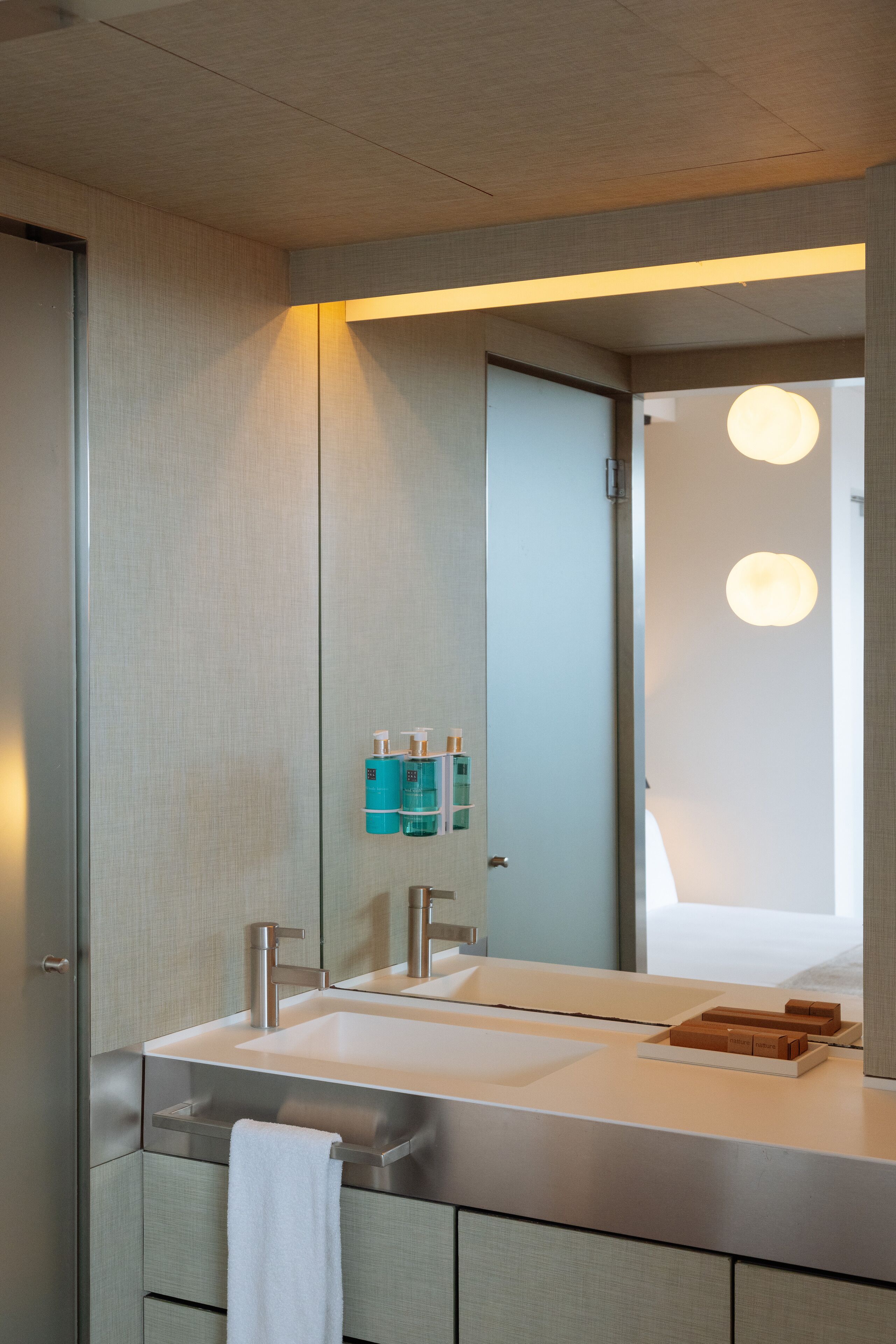 Ein modernes Badezimmer mit großem Spiegel, zwei Waschbecken und einem Handtuchhalter.