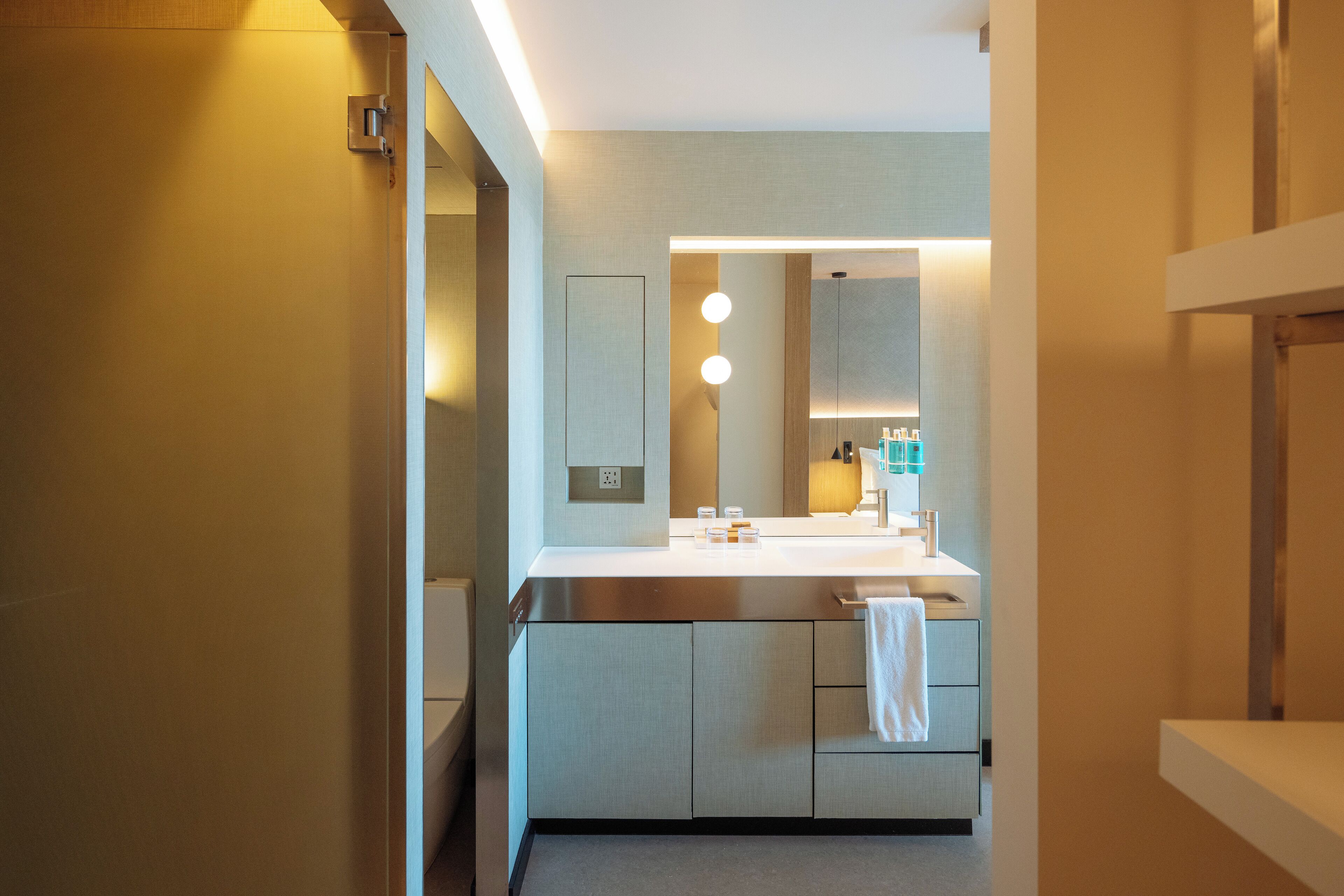 Un baño moderno con un espejo grande, dos lavamanos y un perchero para toallas.
