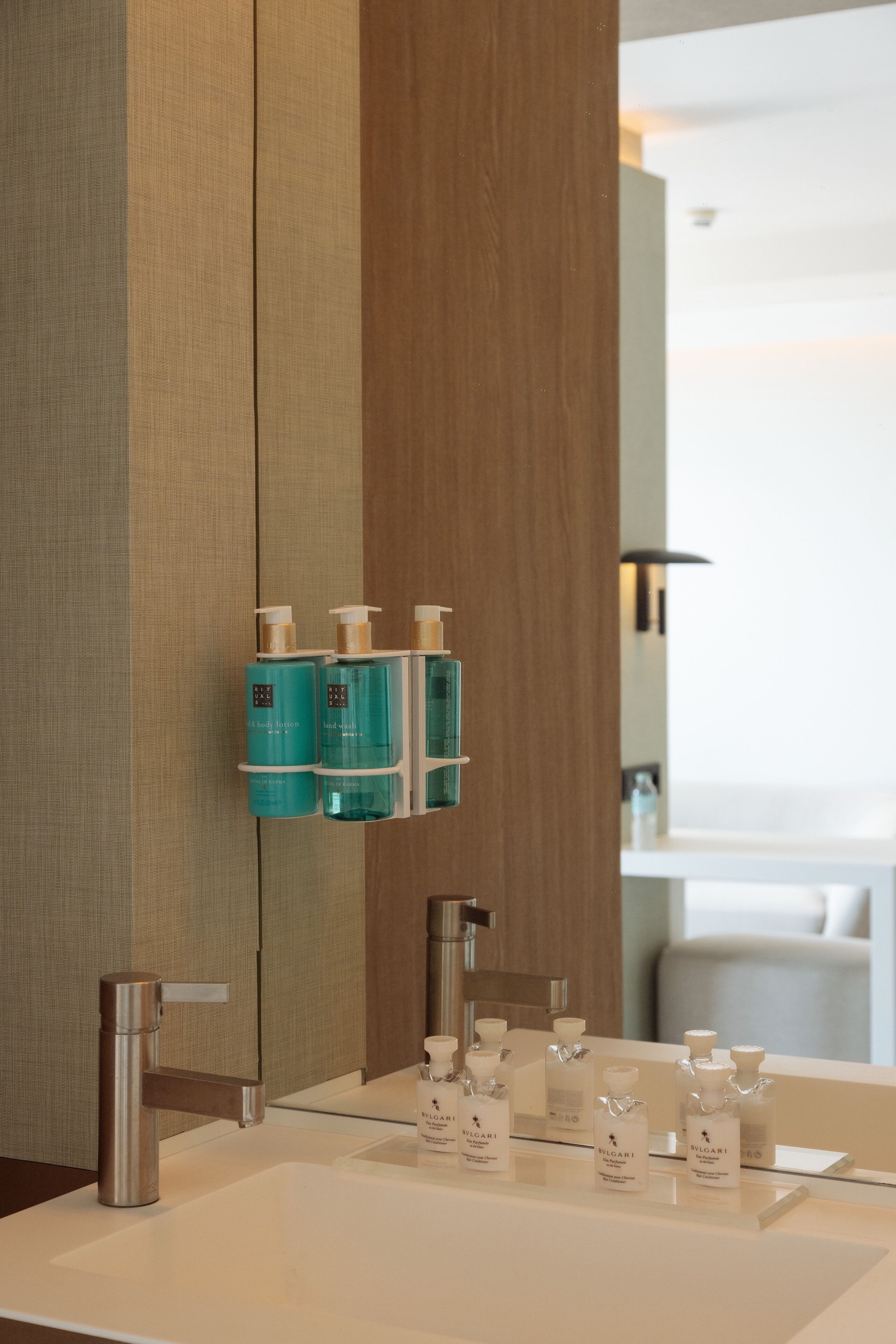 A bathroom with a white sink, two mirrors, and a wooden panel wall.