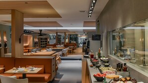 Moderni ravintola, jossa on pitkä palvelutiski, ruokailualue ja buffetpöytä.