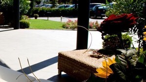 Un espace extérieur aménagé, abrité et doté de mobilier en osier et de plantes en pot.