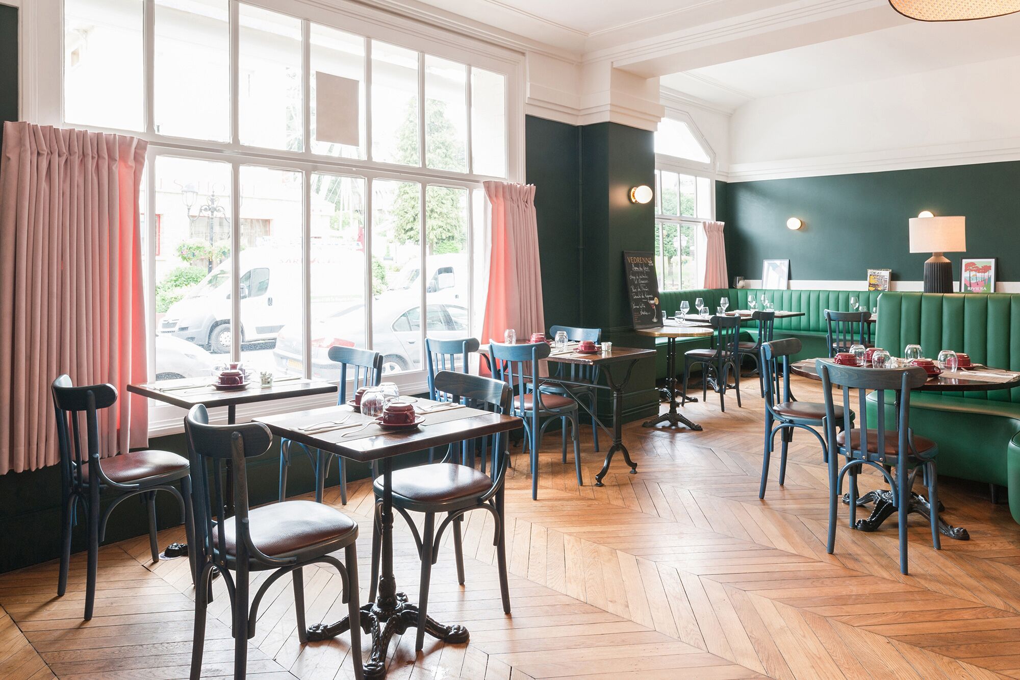 Un ristorante con pavimenti in legno, sedute verdi e tavoli con sedie.