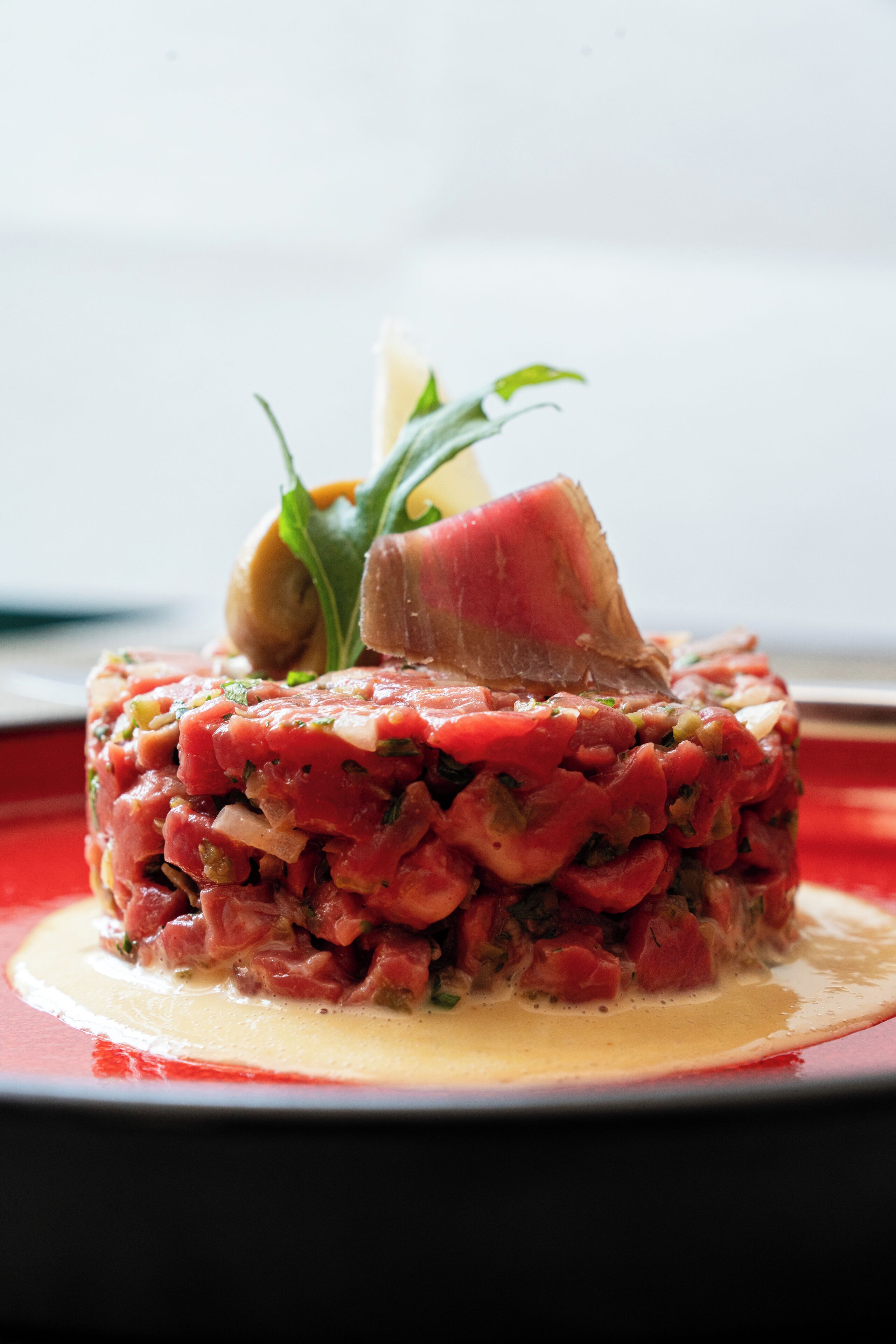 Une assiette de steak tartare, agrémentée d’une garniture.