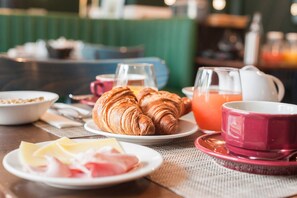 A breakfast setting with croissants, cheese, ham, and orange juice on a table. - The Originals Boutique, Hôtel Ô Gayot (Bagnoles-de-l'Orne)