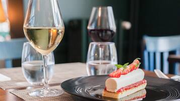 Een dessert op een zwart bord, met een glas witte wijn en een glas rode wijn op de achtergrond.