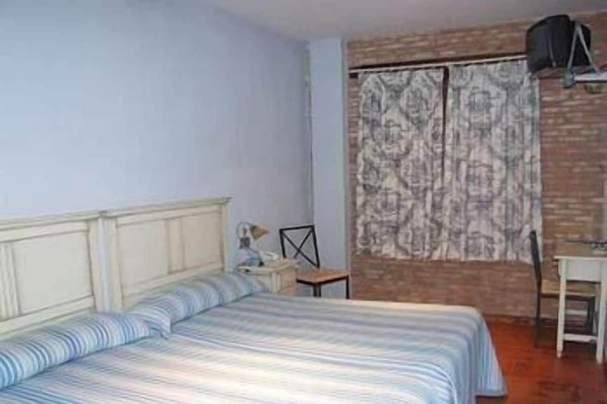 A room with a bed, a desk, and a chair.